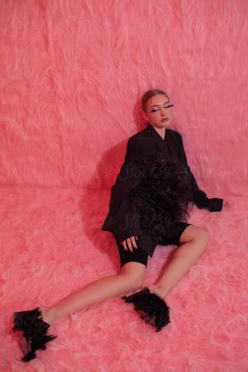 daydreaming model in black relaxing in pink room