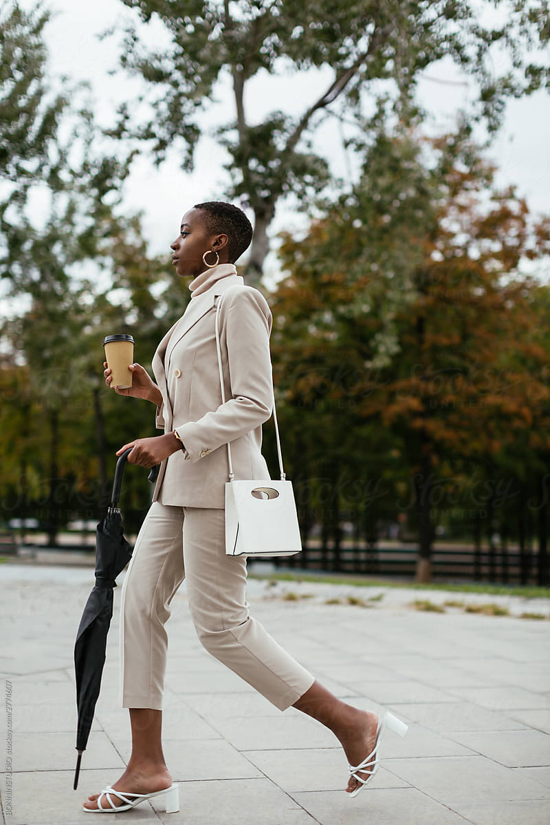 African American woman with drink to go walking in park