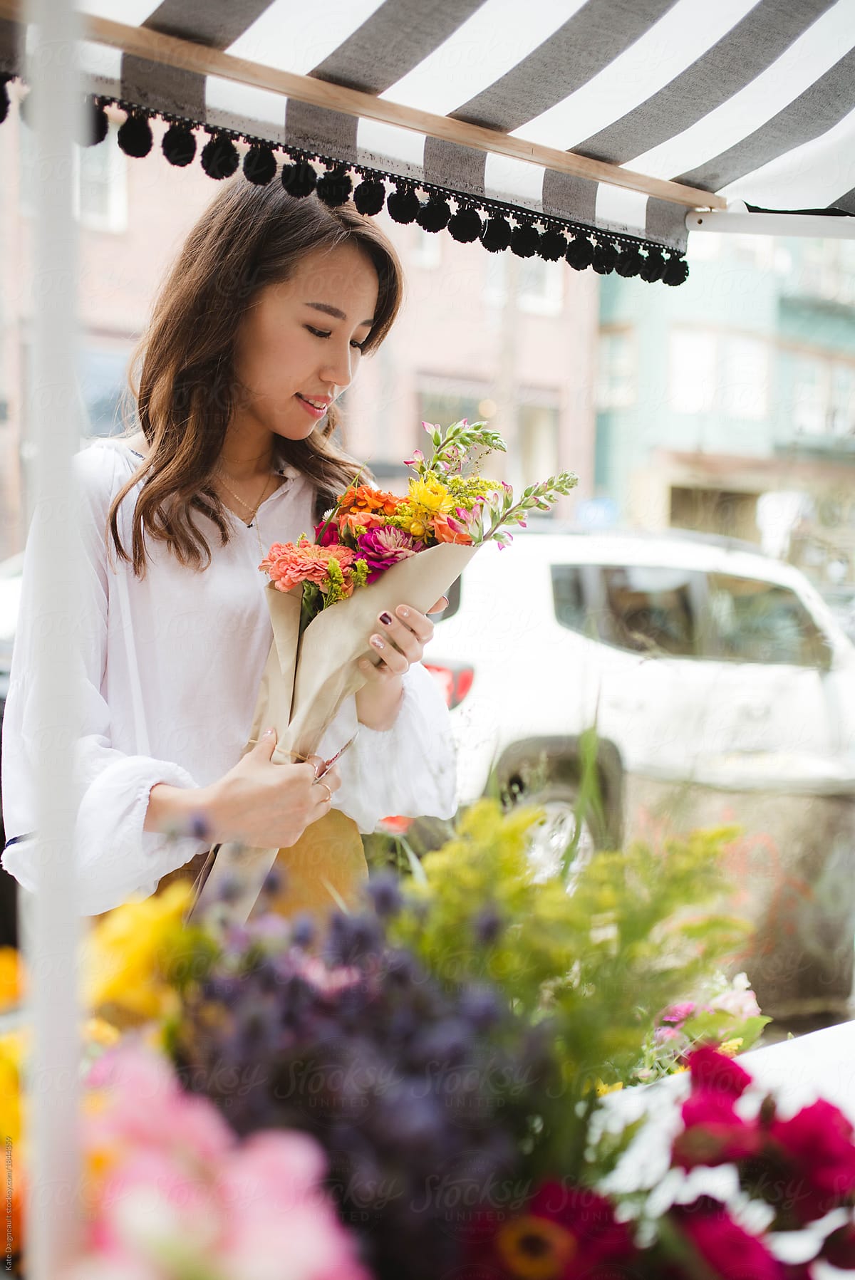 Young woman buying flowers from a city flower cart