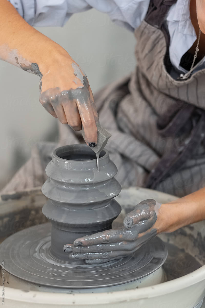 Crop craftswoman wetting clay vase