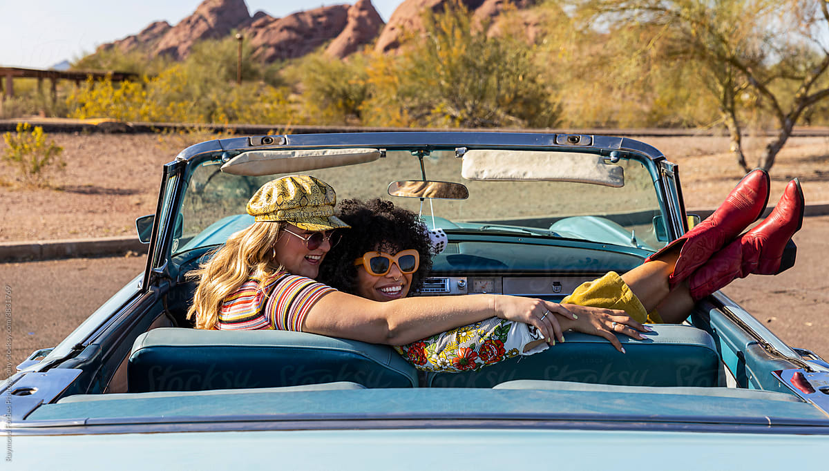 Happy Friends Talking in Vintage car on road trip with Red cowboy boots