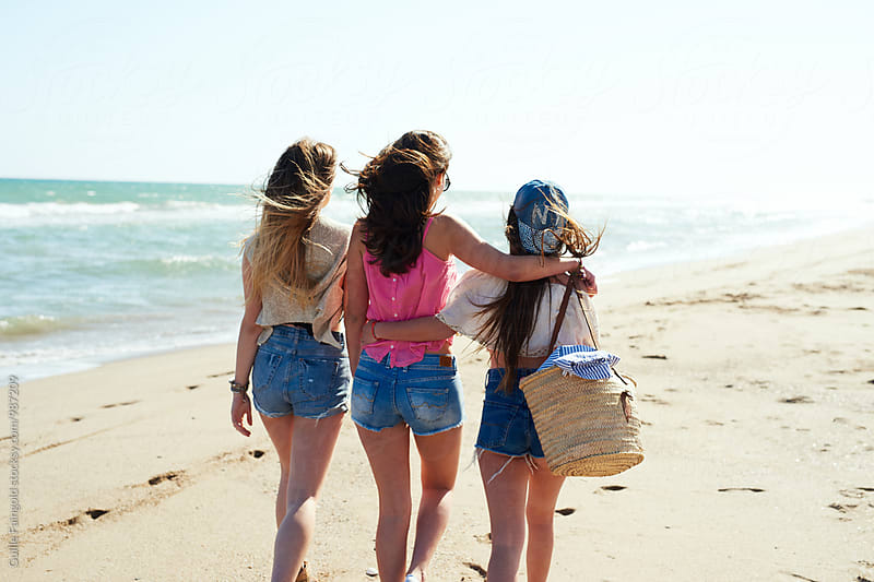 Back view of girls walking along beach