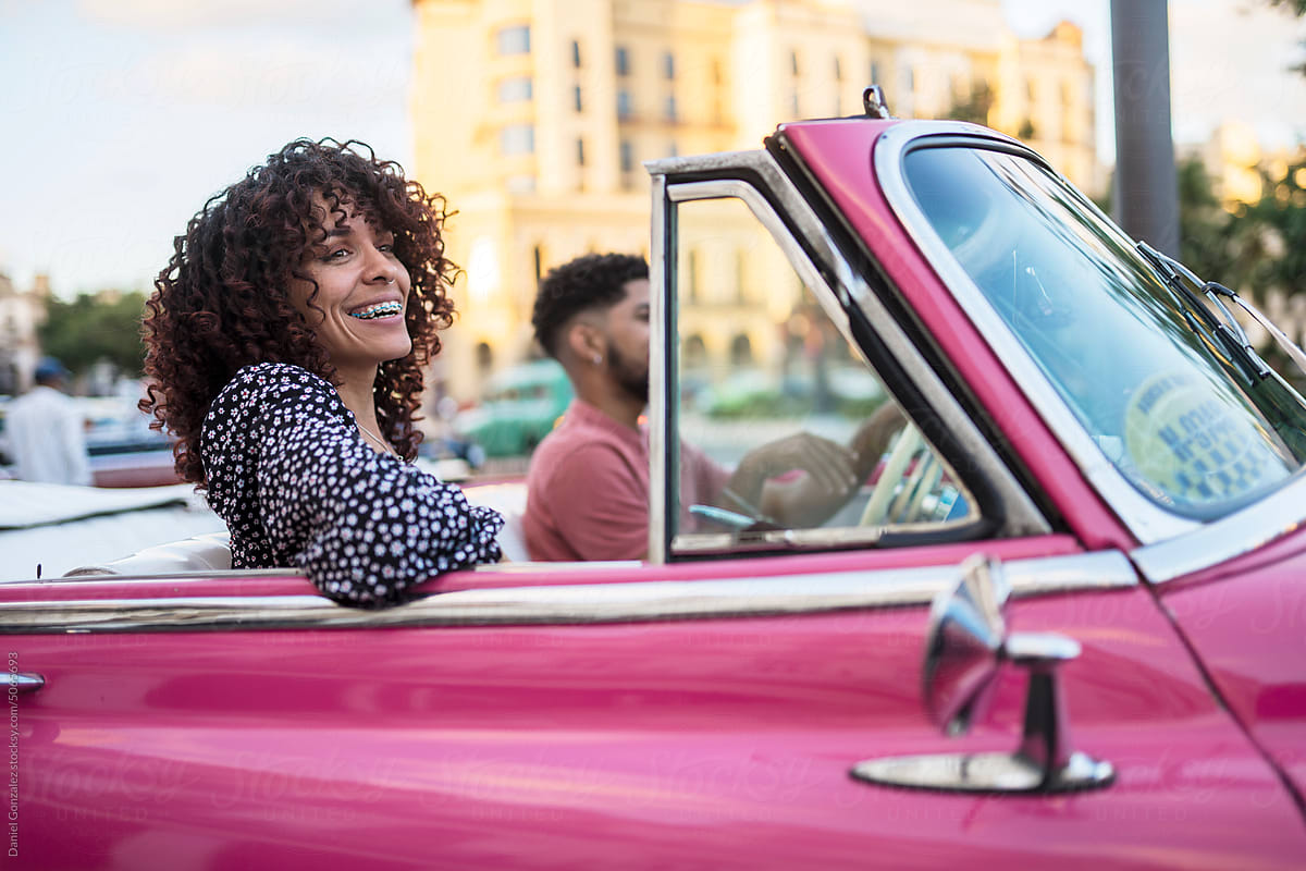 Cheerful woman riding in convertible with boyfriend