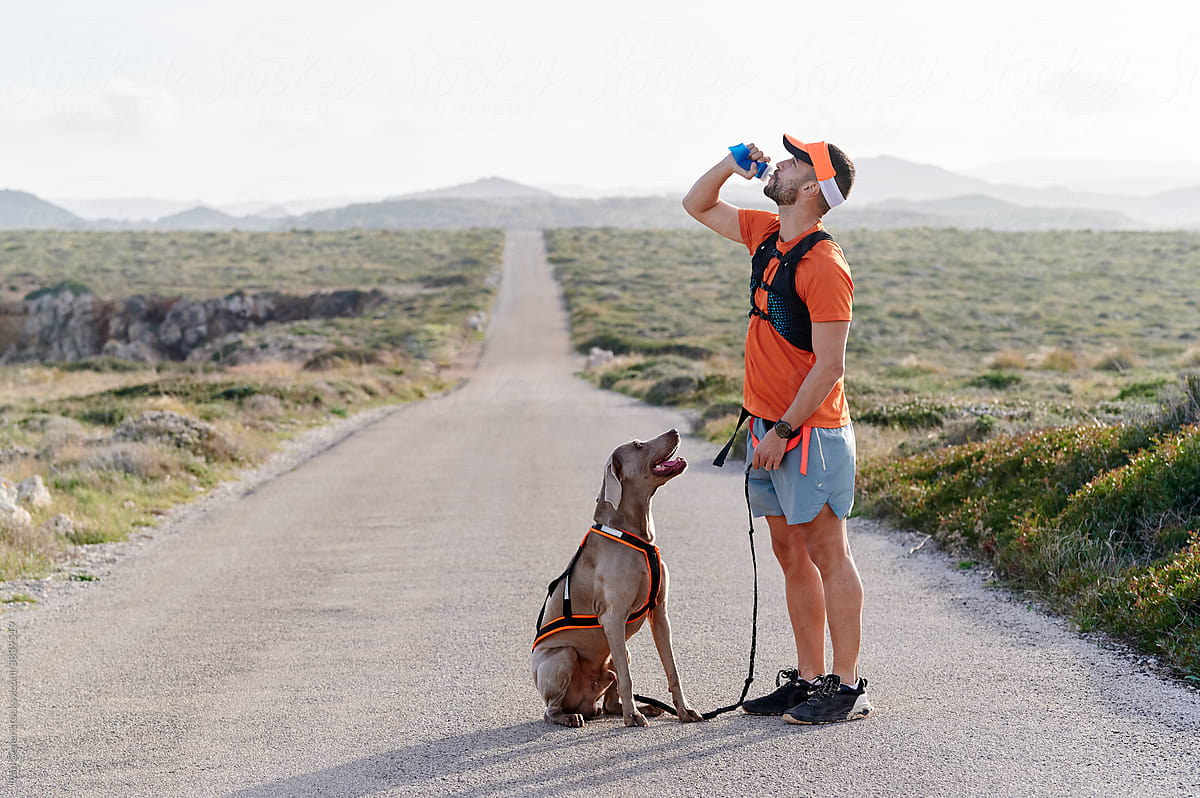 Man drinking water during a run with his dog