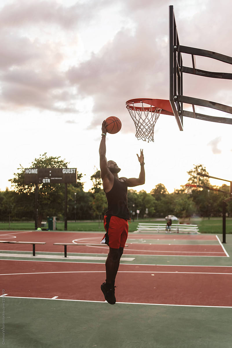 An attractive young black man playing basketball o on a sunny day