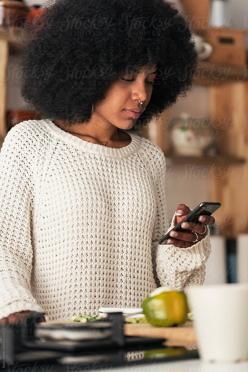 Beautiful Black Woman Using Mobile In The Kitchen Del Colaborador De Stocksy Santi Nuñez 