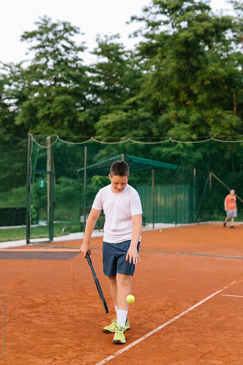 Young boy on a tennis court practicing tennis
