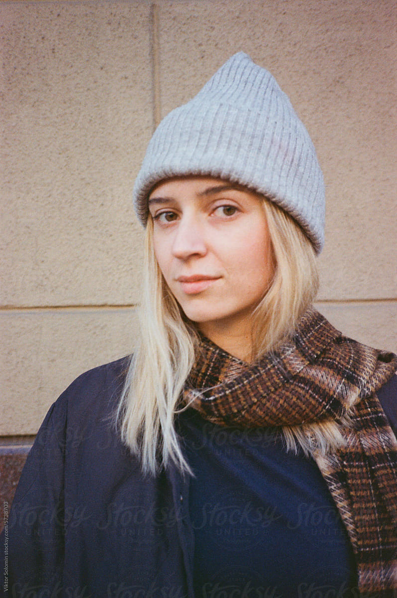 Young woman in warm clothes and hat looking at camera