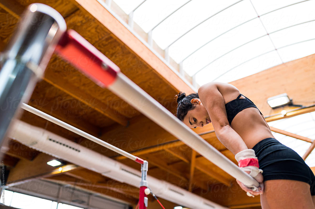 young artistic gymnast woman performing and training uneven bars