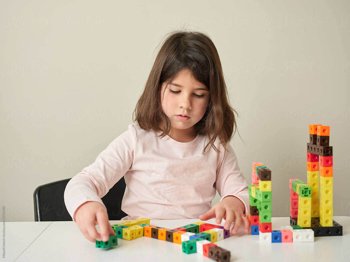Girl building castle from colourful blocks.