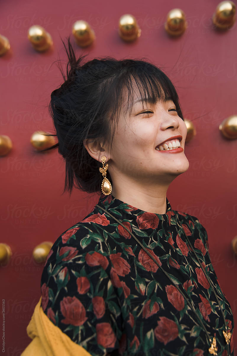Carefree woman smiling by red Chinese temple doors