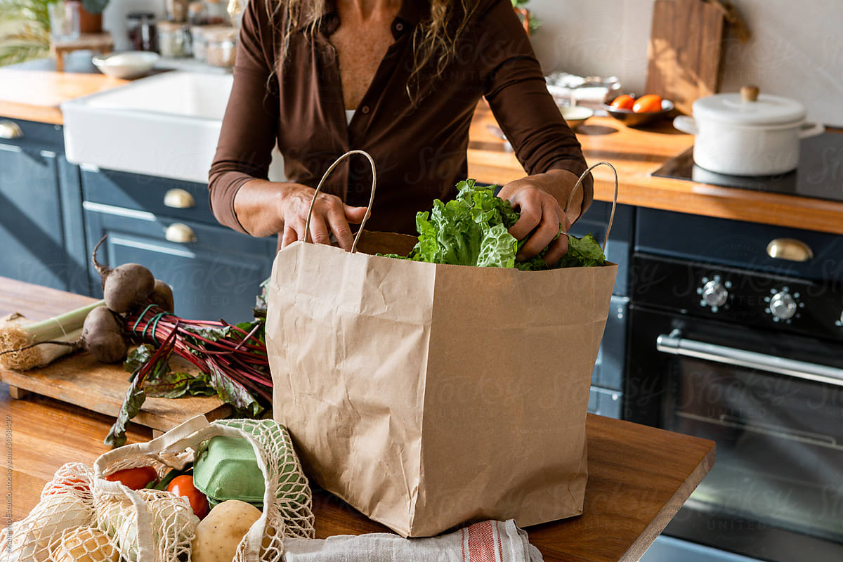 Crop woman with groceries in kitchen