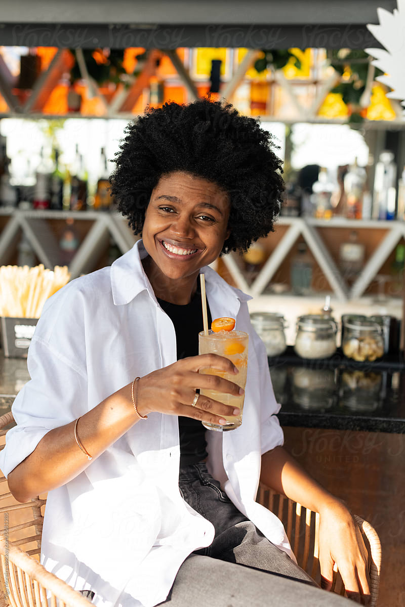 Smiling black woman with a cocktail in a bar