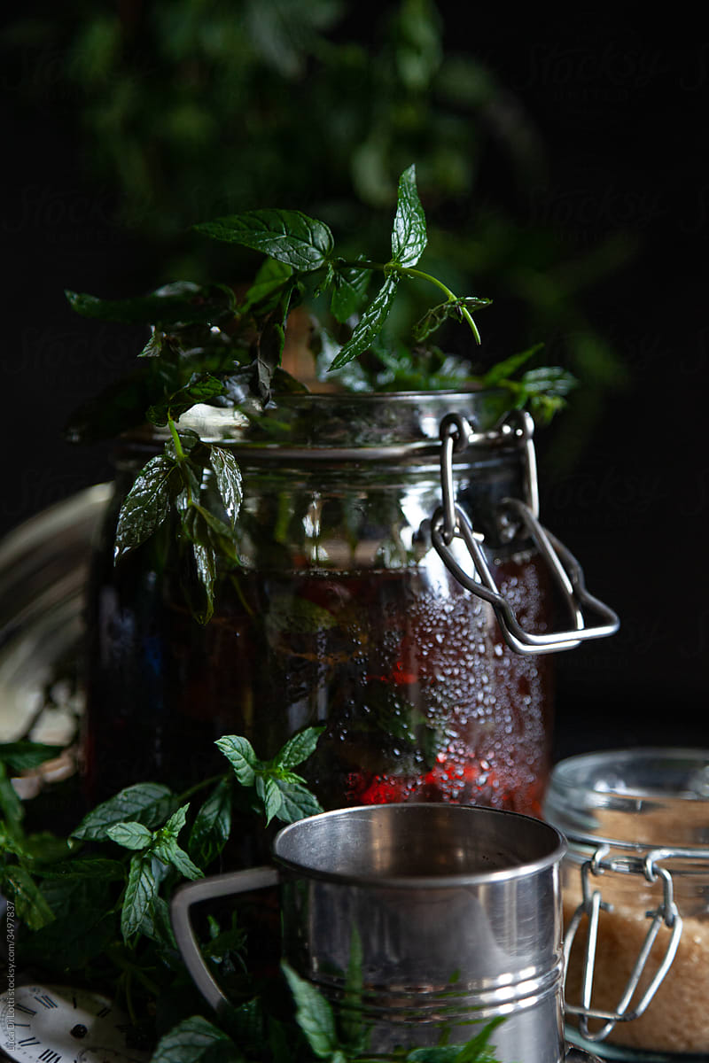 A jar filled with tea with mint leaves, covered with droplets