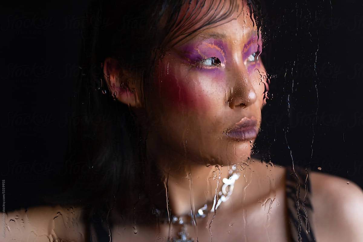 Asian woman with fashion pink makeup through wet glass