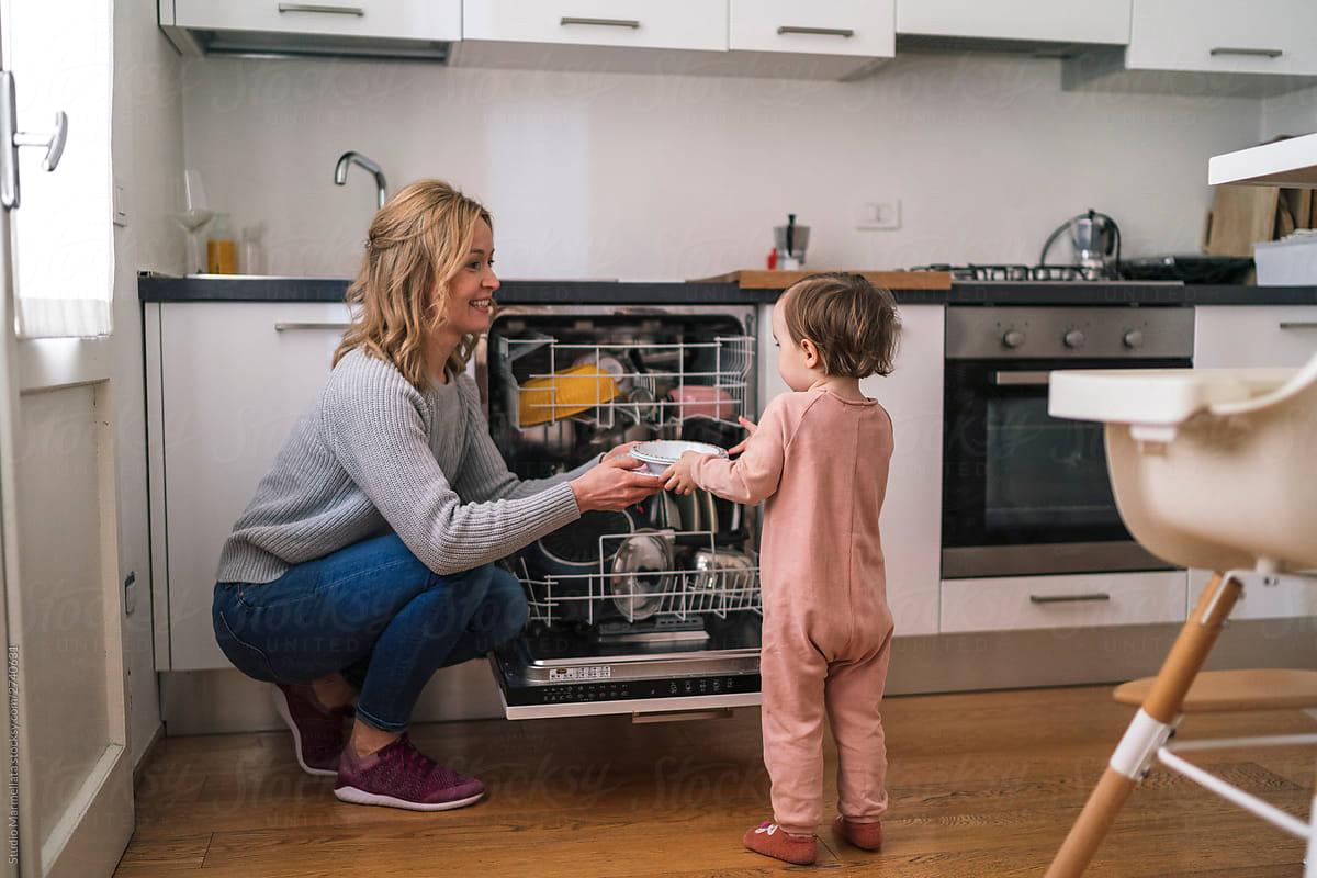 Mother and daughter loading dishwasher at home