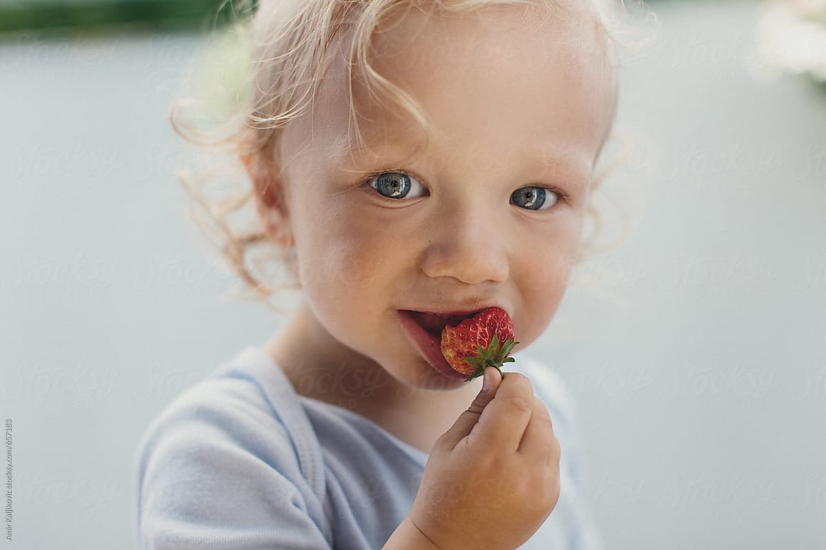 Toddler eating a sweet and tasty strawberry