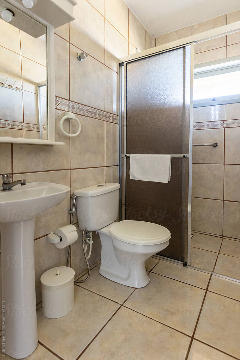 Clean vintage hotel room bathroom with shower, toilet and washbasin
