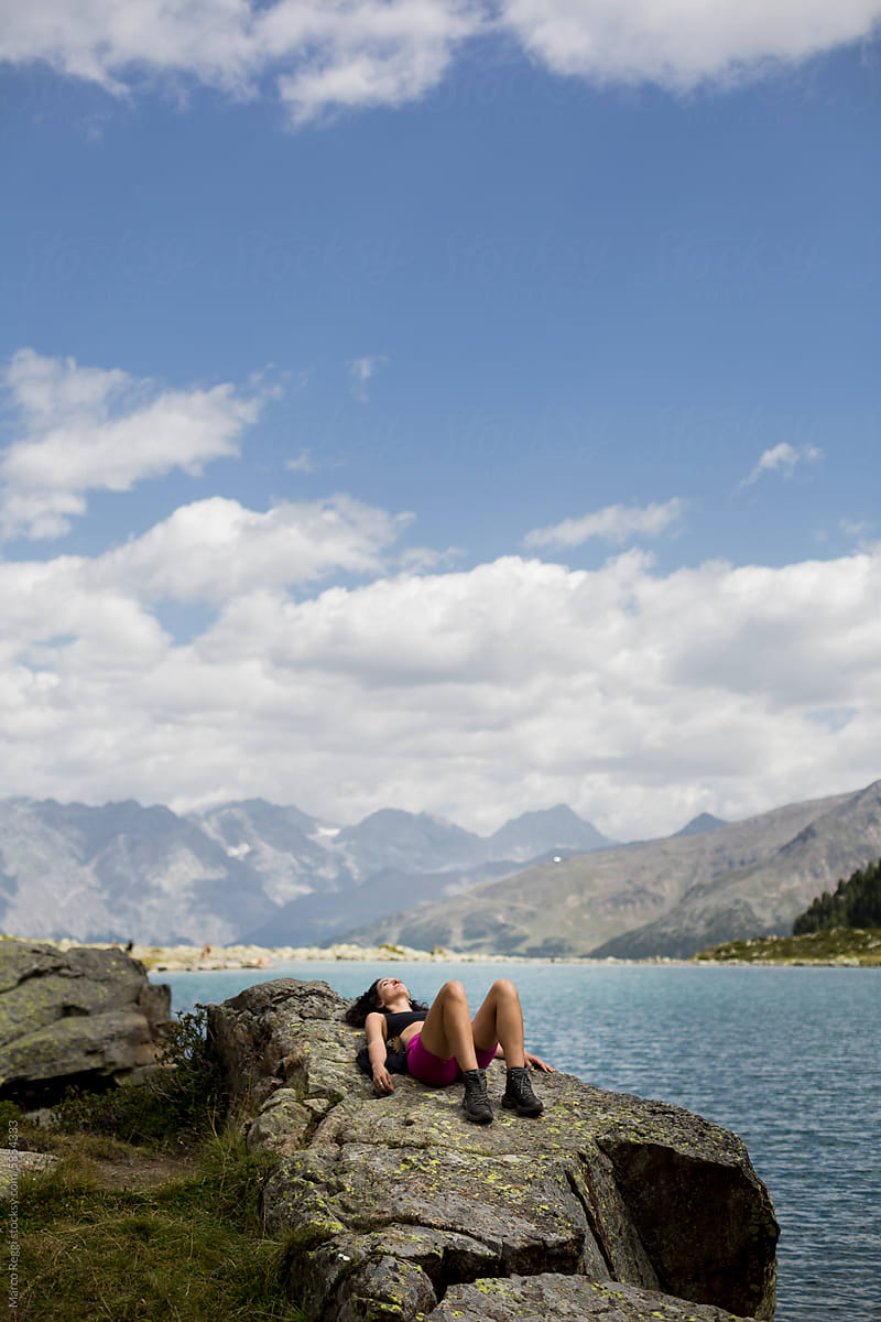 woman rests on a stone on the shore of the mountain lake