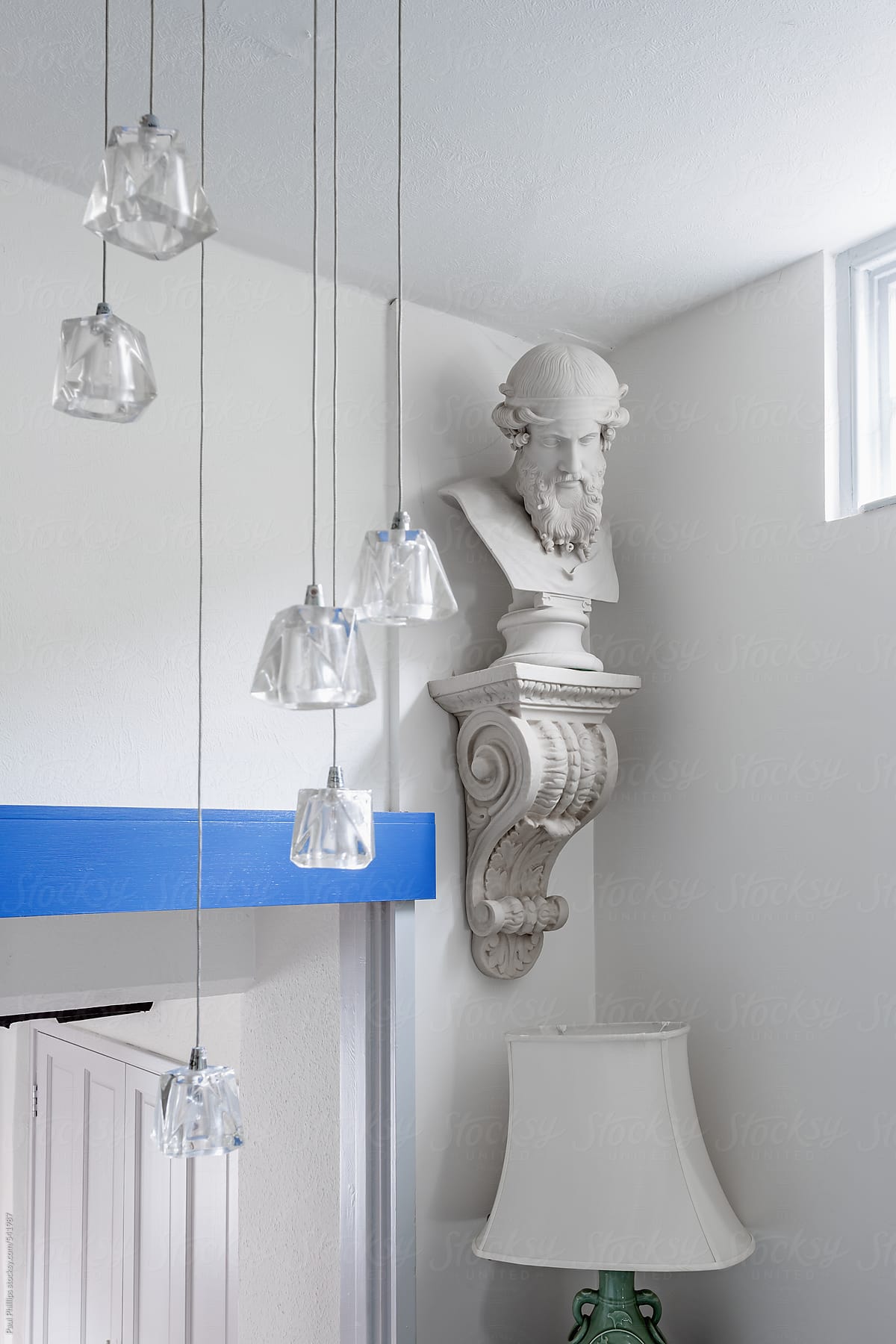 Corner of a white room with a wall statue and hanging in the corner