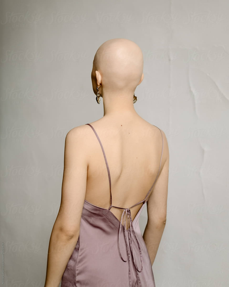 Portrait of a young bald girl in a tender dress. Minimalist studio portrait
