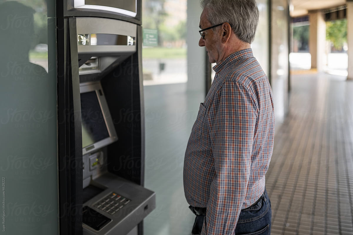 senior man at an ATM withdrawing cash