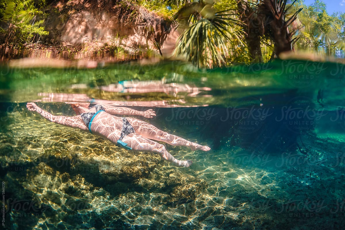 Woman underwater glows in sunlight shining through surface of Florida spring river