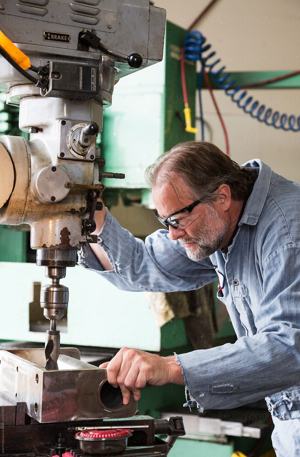 Factory worker focuses on drill press