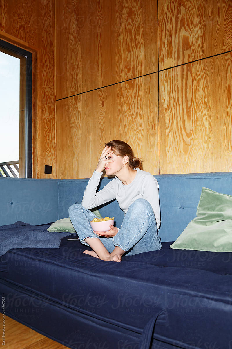 Woman watching scary movie on sofa