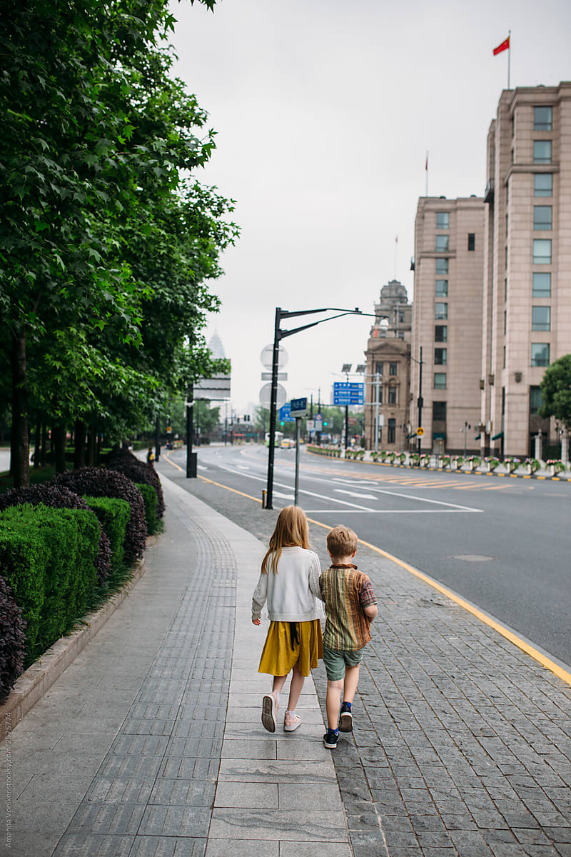 Two young siblings walks together along a city street in Shanghai
