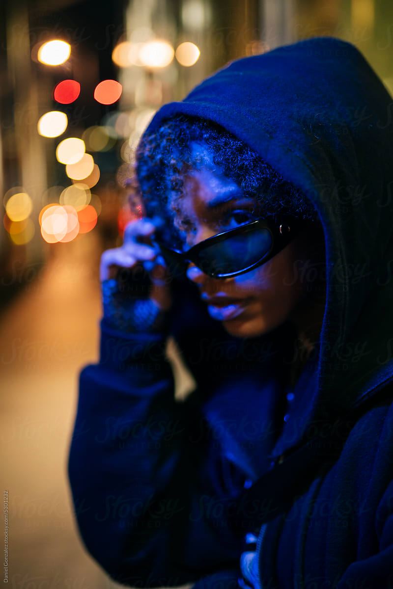Cool black woman in sunglasses on night street