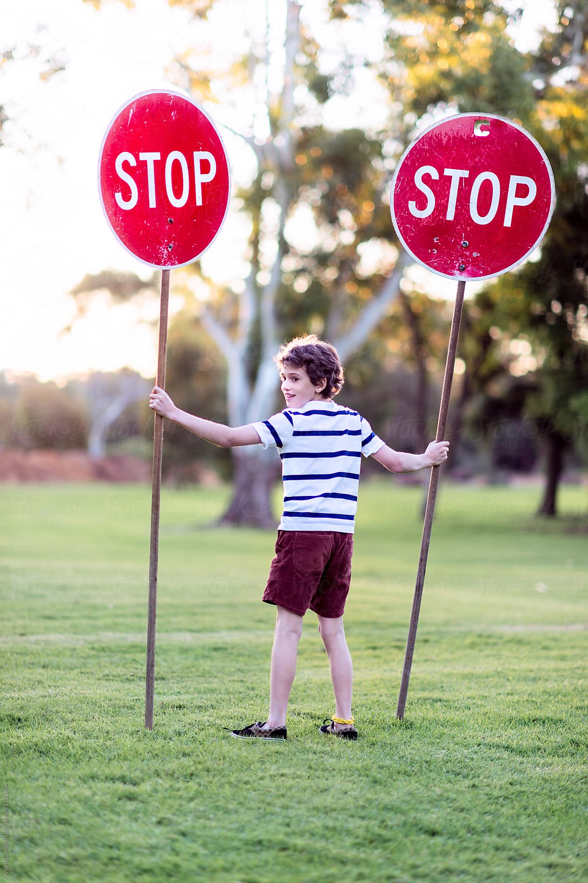 Boy with two stop signs in park