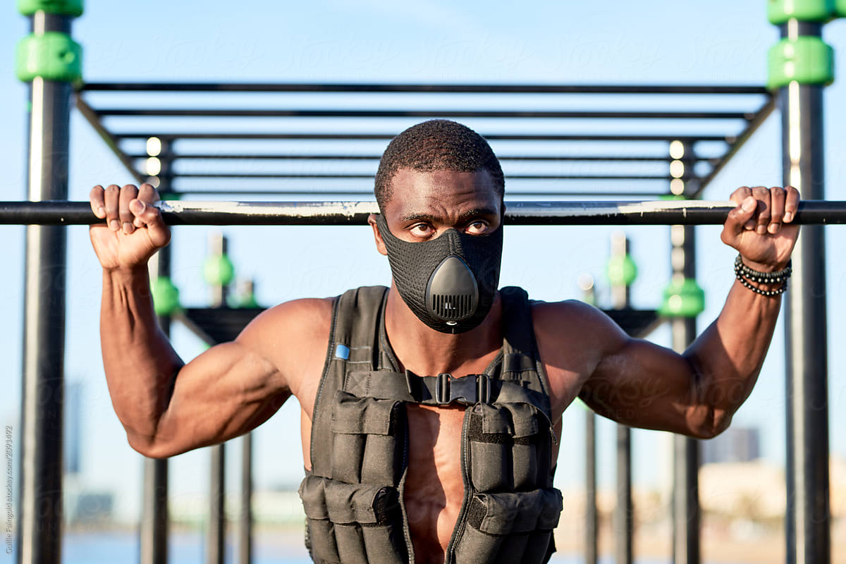 Muscular sportsman in respiratory mask and weight vest