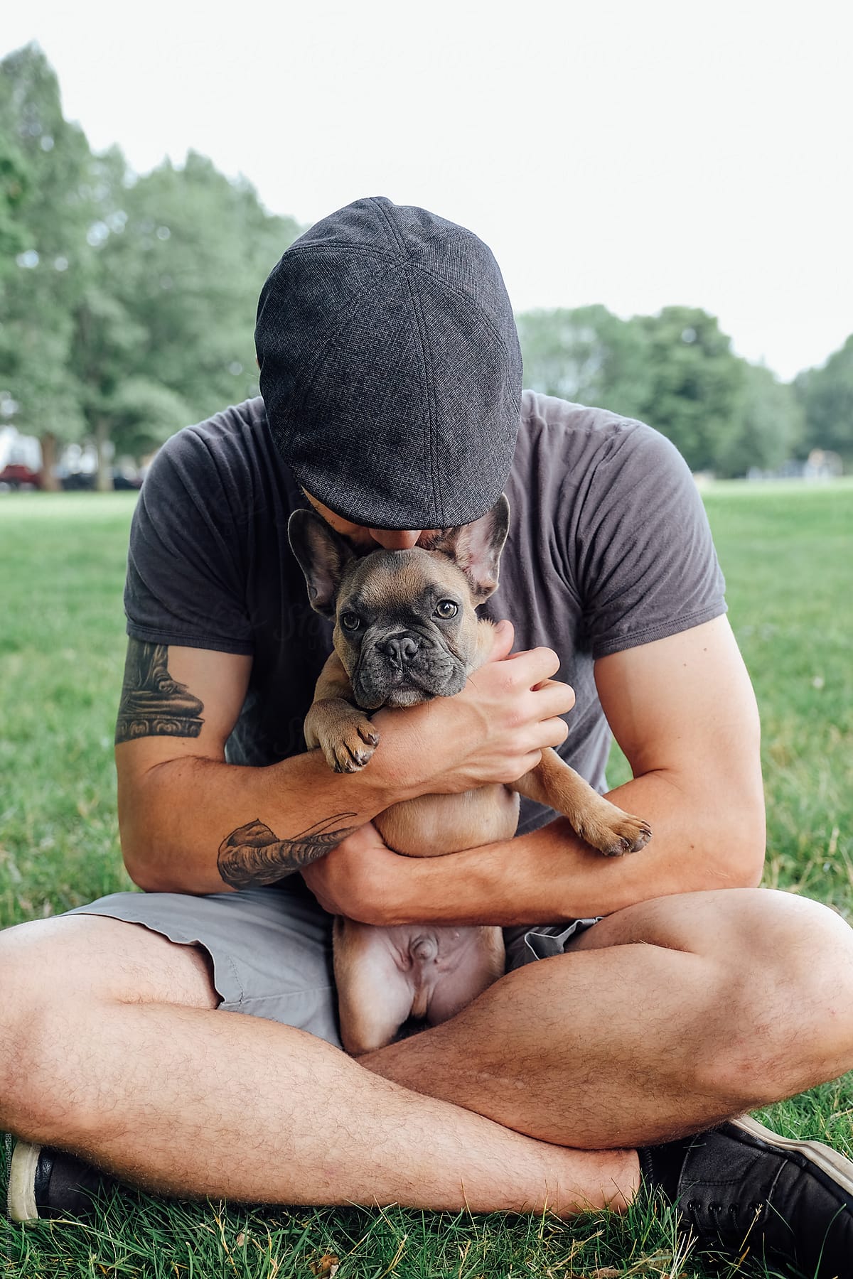 A french bulldog puppy being held and cuddled by a strong caucasian man.