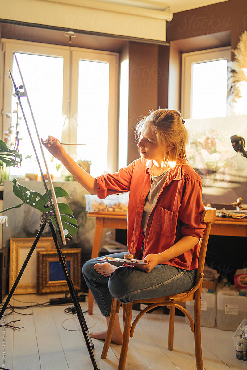 woman is painting in her cozy studio