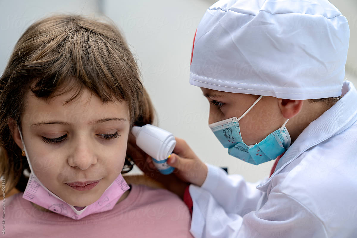 Doctor checking ear of little sister