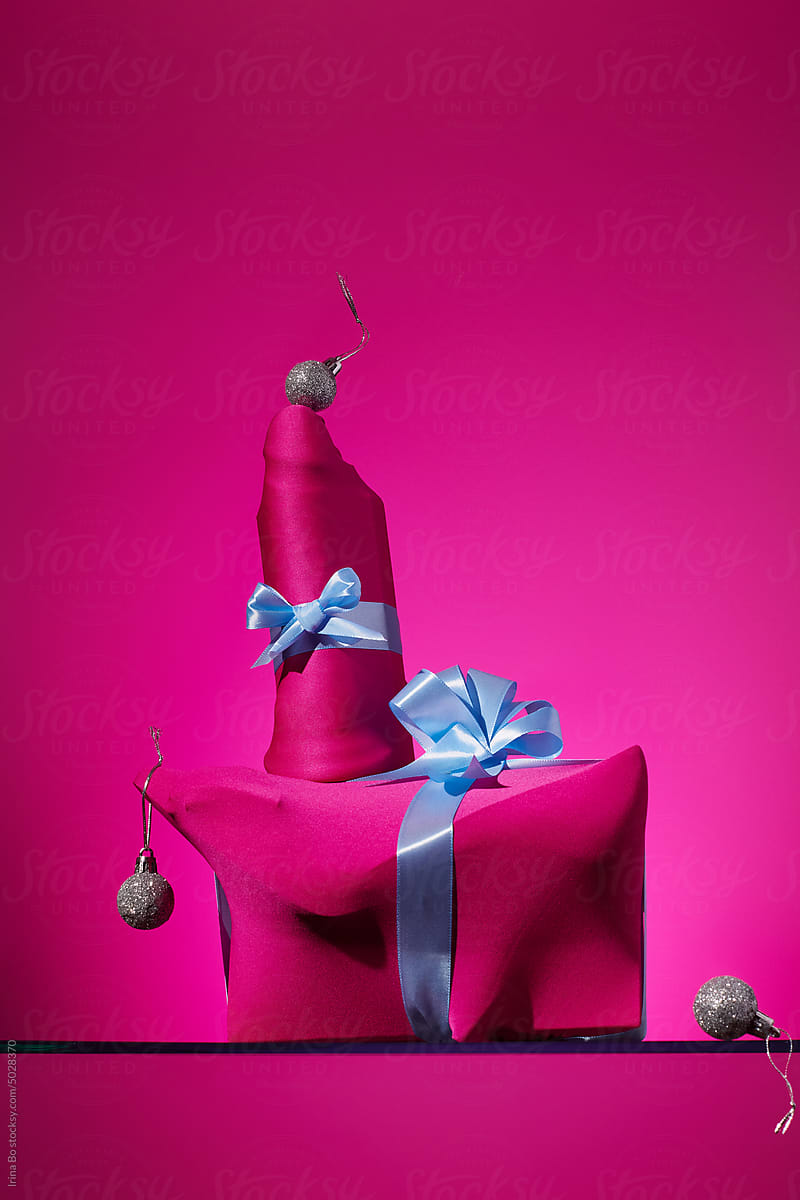 Dildo and shoes in elastic festive packaging on a pink background