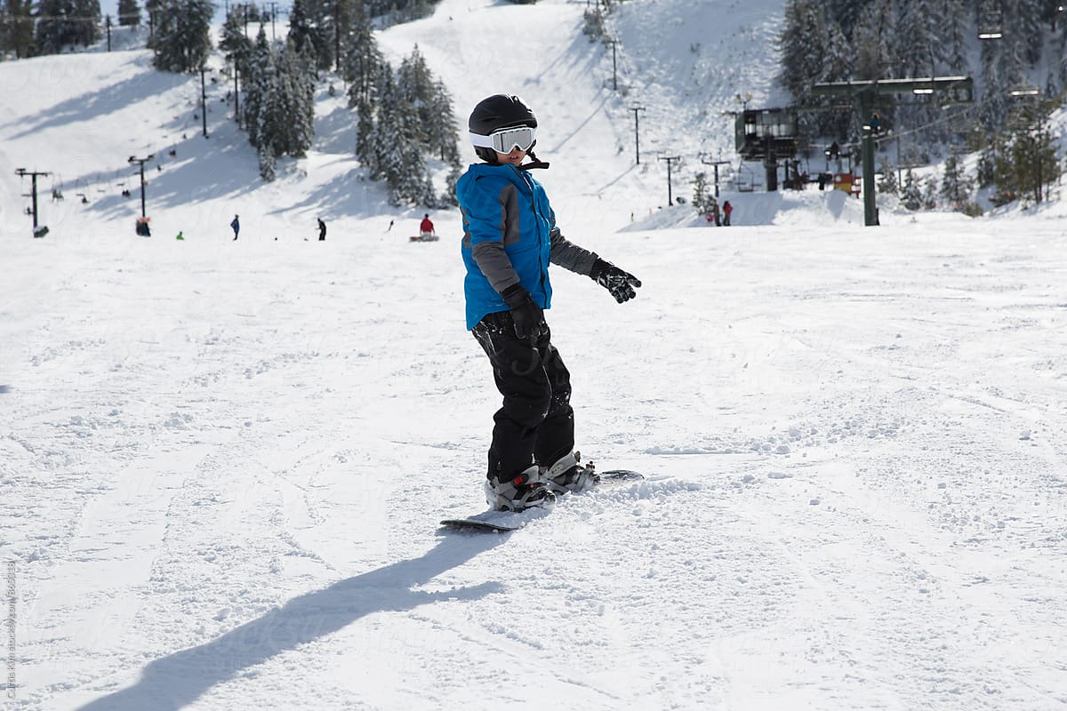 Young boy snowboarding down a hill