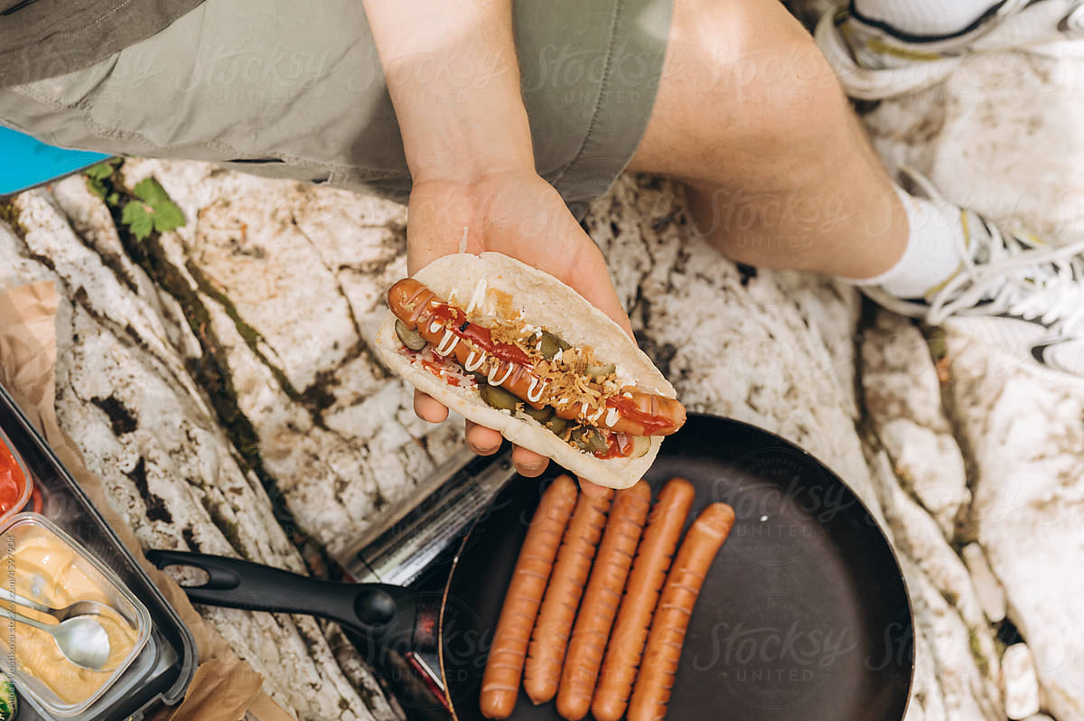 Crop hiker preparing flatbread hot dog