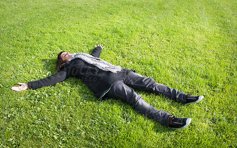 Young woman with open arms lying on the grass by ACALU Studio - Stocksy ...