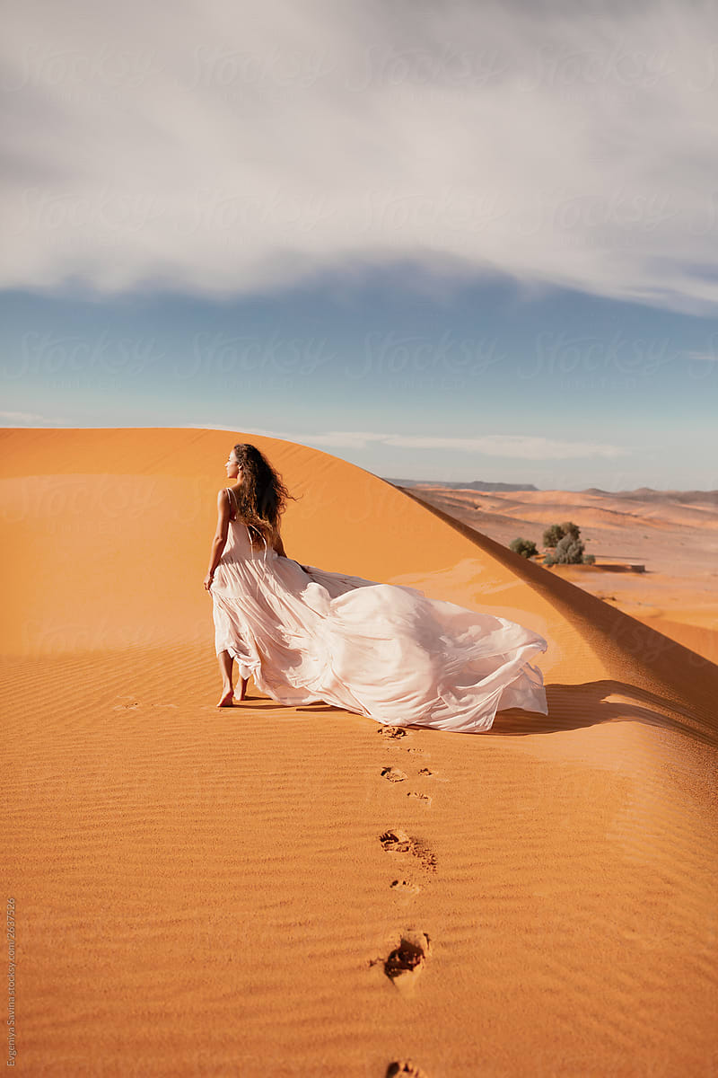 A Long Haired Brunette Woman Walking In The Desert In A Airy Wavy Pink
