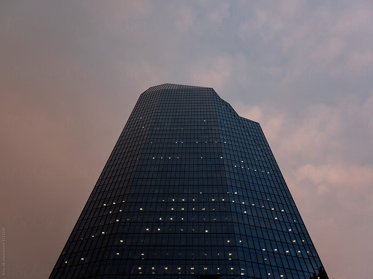 An interesting shaped office tower against a pink & blue sky at night.