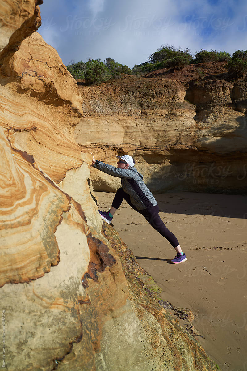 Woman stretching leg muscles post workout on beach