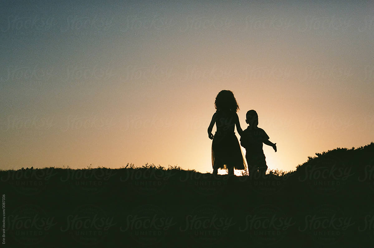 Silhouette of brother and sister at sunset