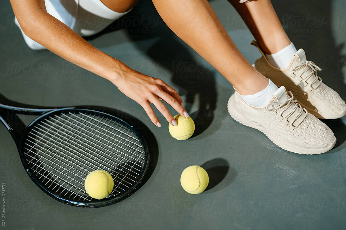 A woman is sitting on the floor of a tennis court