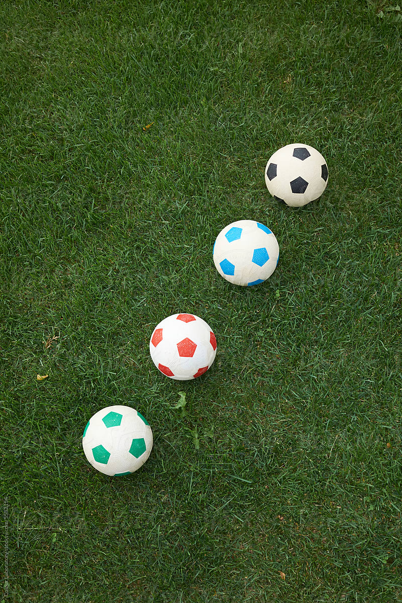 Minimal photo of colourful footballs with green grass background