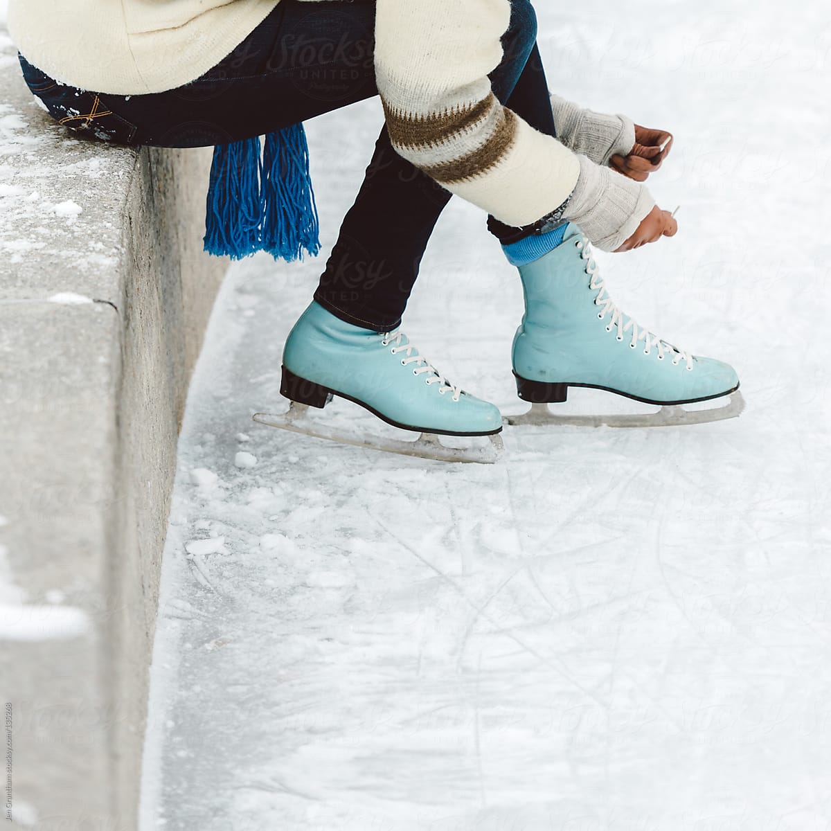 Woman lacing up vintage blue ice skates