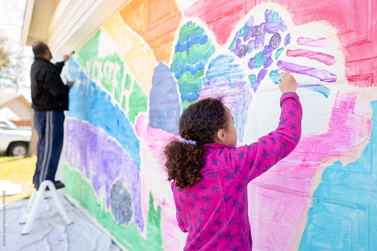 Girl paints colorful Easter mural with father