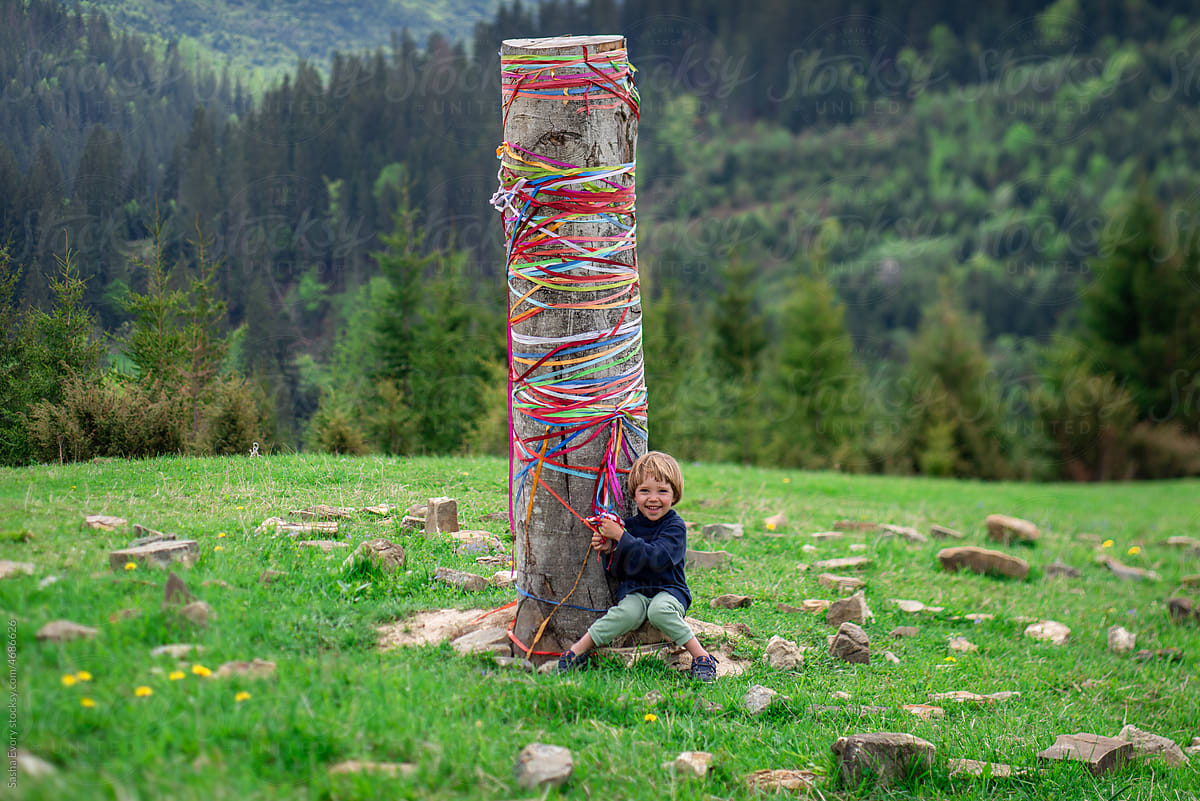 Boy sitting by a pole with ribbons