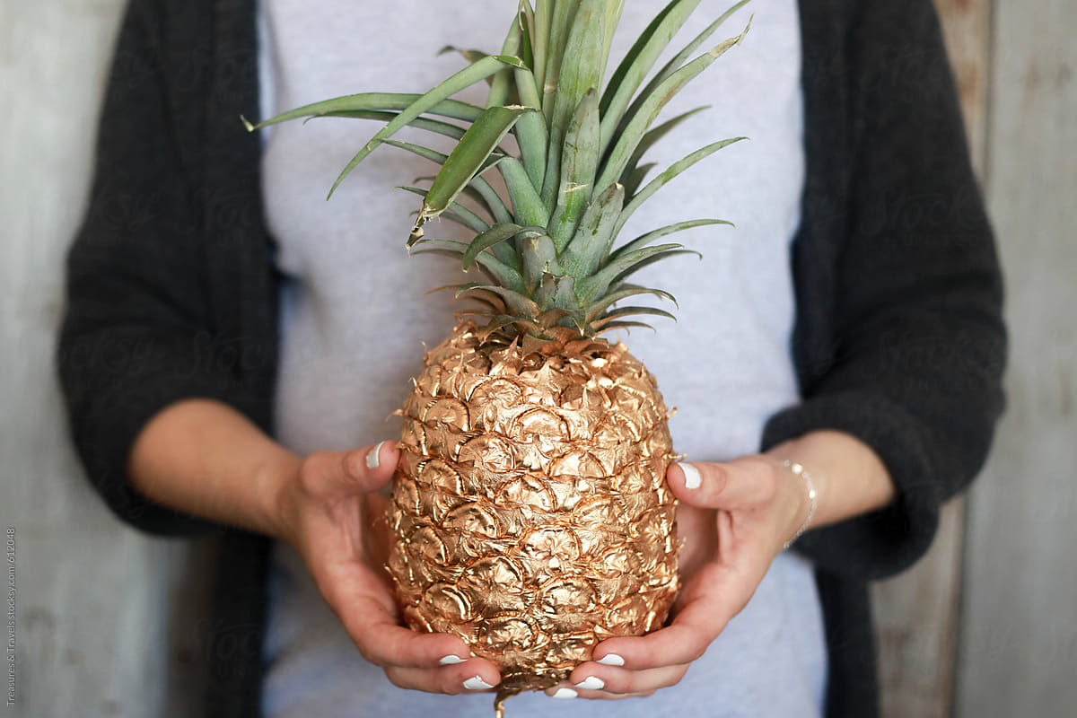 Woman holding a gold painted pineapple fruit